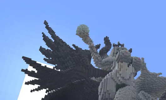 Giant winged warrior statue holding an orb, seen from below